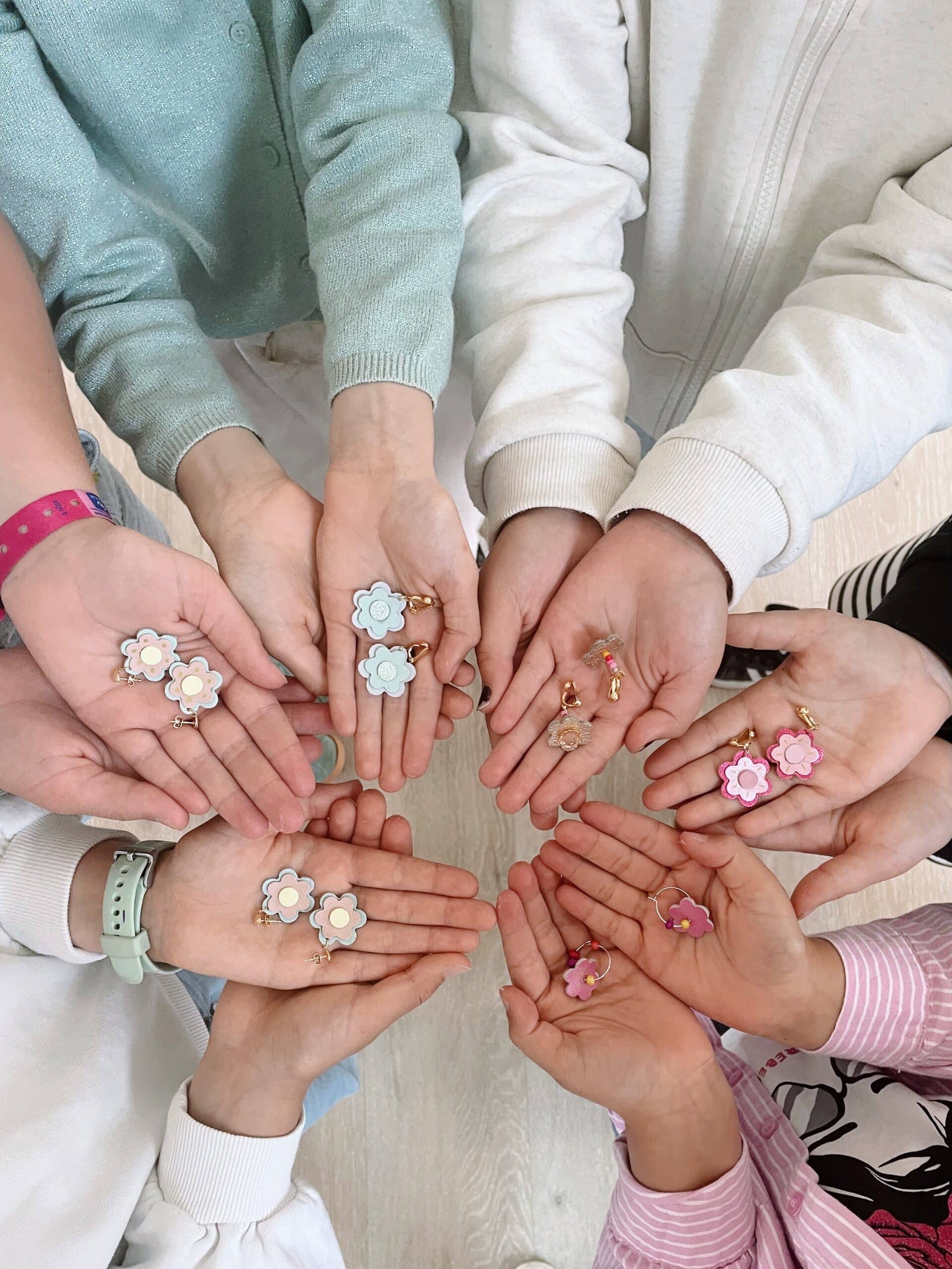 Atelier anniversaire enfants – bijoux en cuir Côte d'Opale | Du vent dans mes valises Enfants tenant leurs créations en cuir – boucles d'oreilles fleurs dorées réalisées lors d'un atelier anniversaire créatif sur la Côte d'Opale