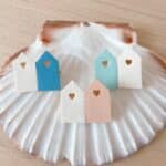 Trois broches duo cabines de plage en cuir surcyclé — Bleu Wimereux, Bleu Hardelot et Rose Berck — sur grande coquille naturelle