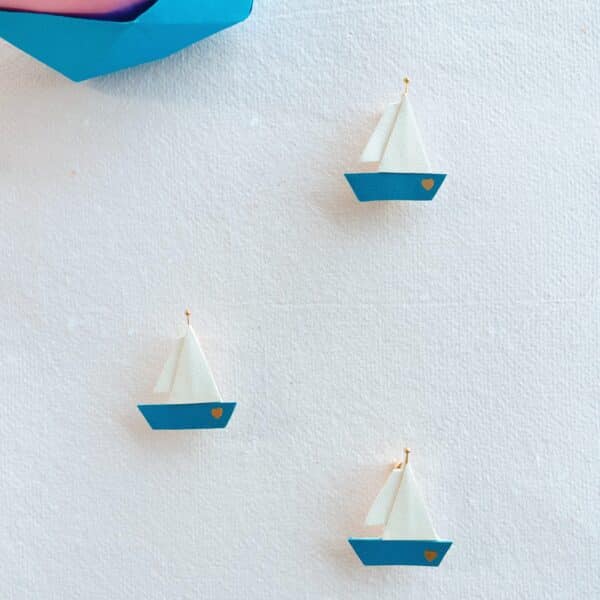 Trois broches voilier en cuir surcyclé bleu et blanc, cœur doré, sur fond blanc