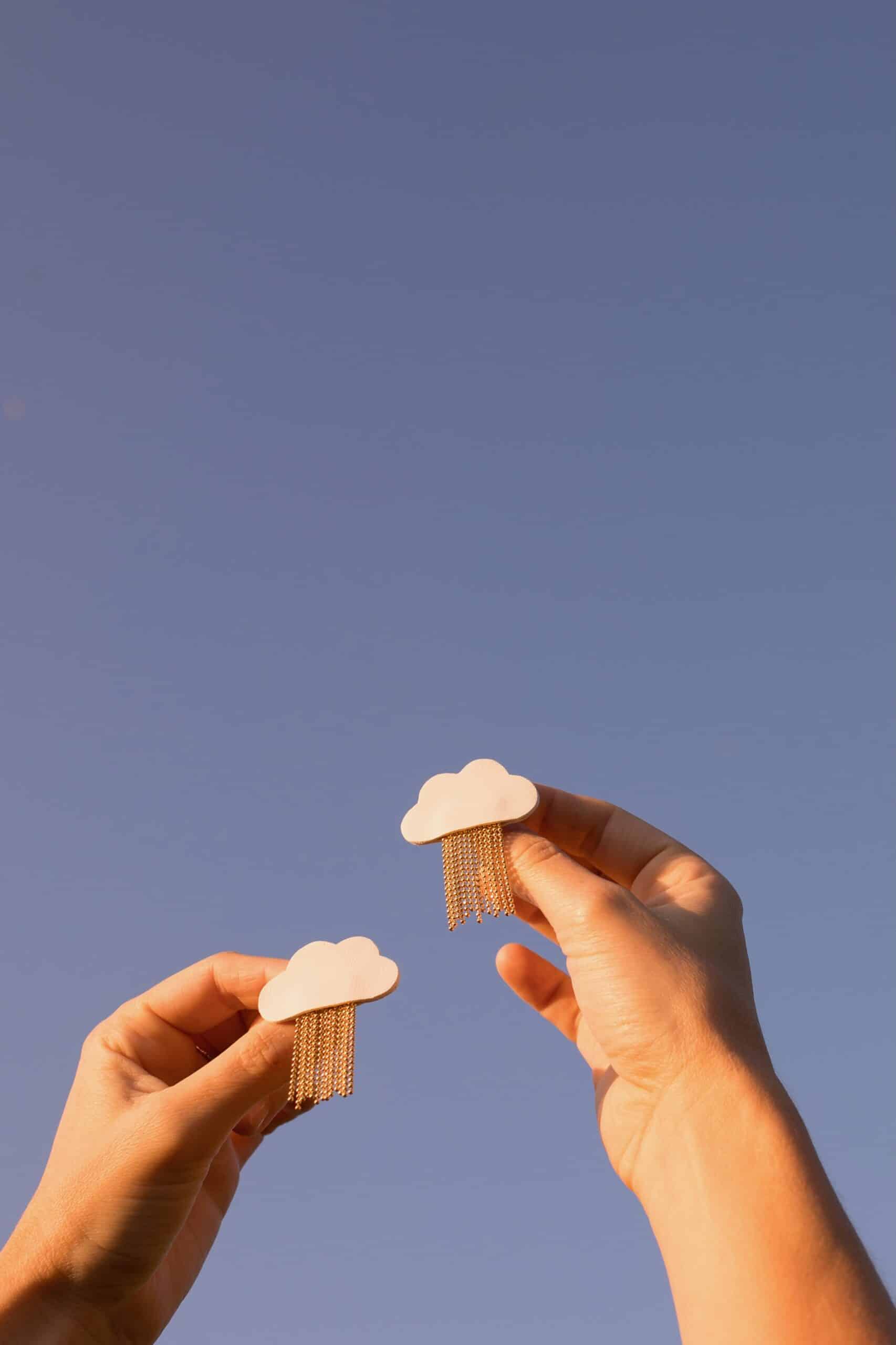 Broche nuage L'Ondée cuir blanc pluie dorée — image à la une © Du vent dans mes valises Deux broches nuage L'Ondée en cuir surcyclé blanc, pluie de chaînes dorées, tendues vers un ciel bleu