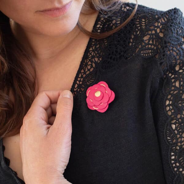 Broche rose fuchsia en cuir avec dorure portée sur une veste noire à dentelle — bijou artisanal poétique Du Vent dans mes Valises