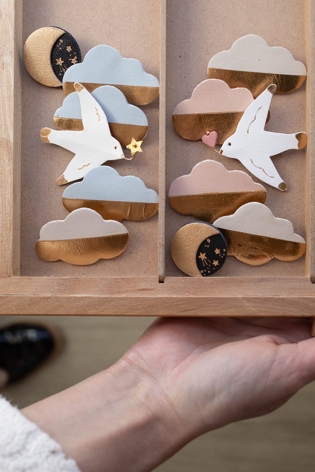 Broche mouette heureuse — collection céleste © Du vent dans mes valises Broche mouette blanche en cuir surcyclé entourée de broches nuages dorés et lunes, collection céleste