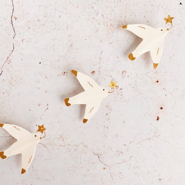 Broche en cuir surcyclé, représentant une mouette portant une étoile dorée dans le bec.