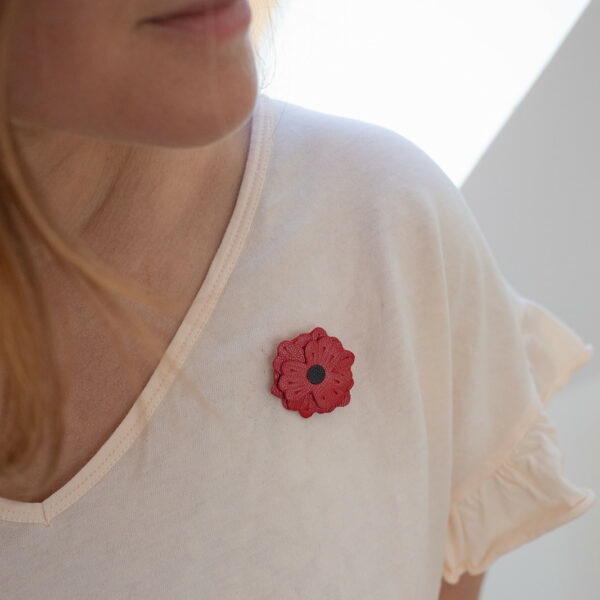 Broche coquelicot en cuir surcyclé rouge portée sur un t-shirt blanc, cœur noir bien visible