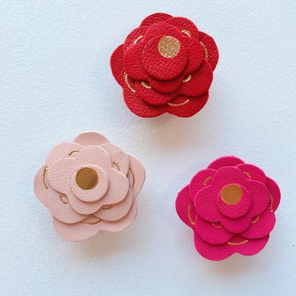 Broche artisanale en cuir surcyclé, rose façonnée à la main avec dorure à chaud, disponible en rouge carmin, rose fuchsia, rose pâle et blanc.