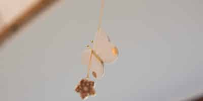 Suspension poétique papillon en cuir fait main, bijou d’intérieur avec fleur de cerisier et quartz rose, à suspendre sous une étagère ou un luminaire.