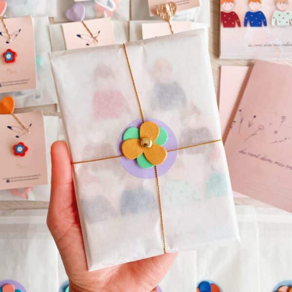 Pochette surprise artisanale contenant une broche fleurie, un pin’s et des trésors poétiques Titre