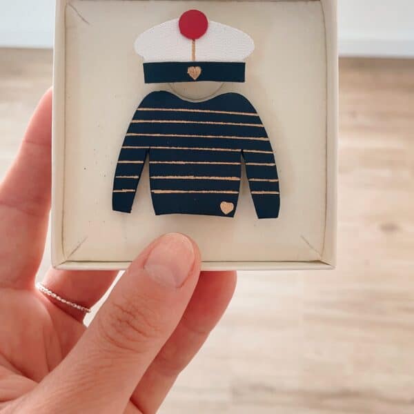 Duo broches marinière et béret de marin en cuir surcyclé tenu en main dans leur écrin