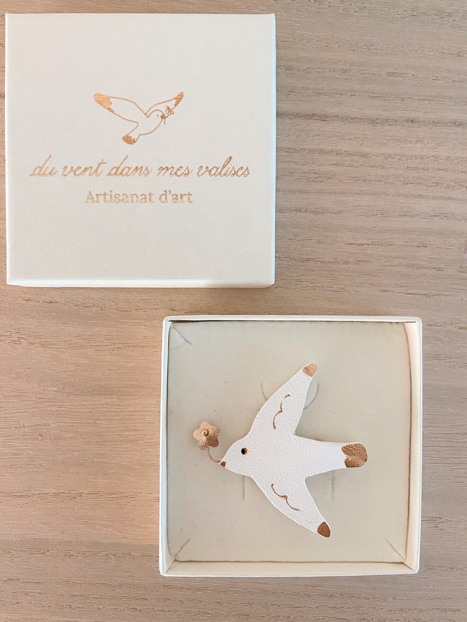 Broche mouette heureuse cuir blanc — dans son écrin © Du vent dans mes valises Broche mouette heureuse en cuir surcyclé blanc et doré avec petite fleur au bec, dans son écrin Du vent dans mes valises