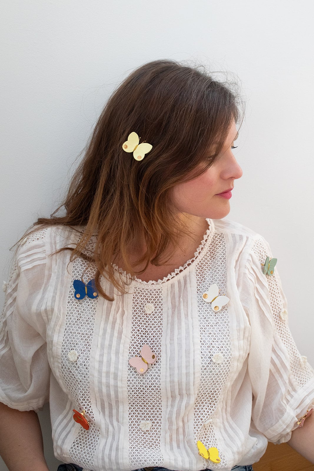 Nuée de broches papillons cuir multicolores portées © Du vent dans mes valises uée de broches papillons en cuir multicolores portées sur une blouse blanche, papillon jaune dans les cheveux