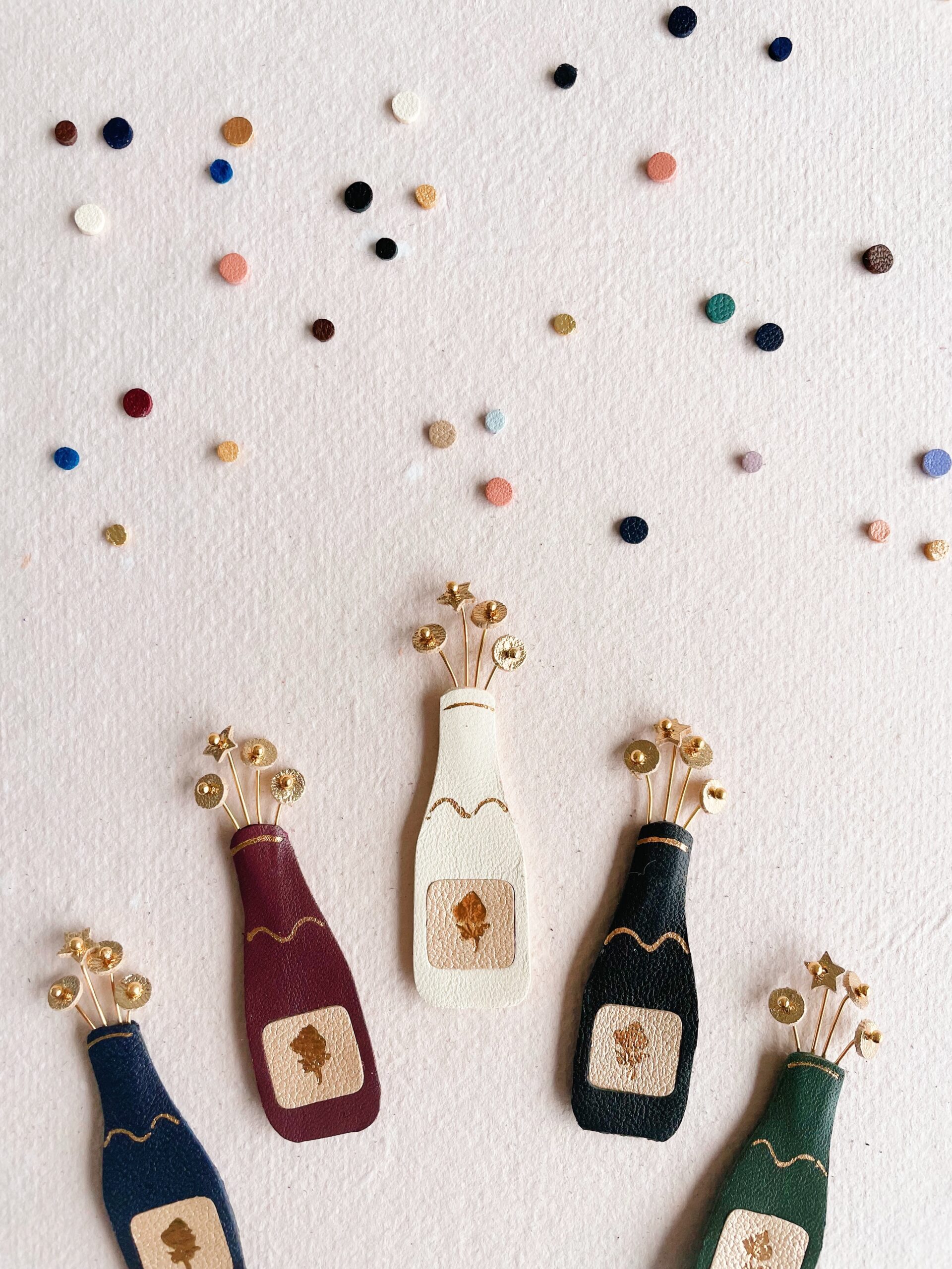 Broche pétillante façon bouteille de champagne artisanale – © Du vent dans mes valises Broche bouteille de champagne artisanale en cuir avec bulles dorées