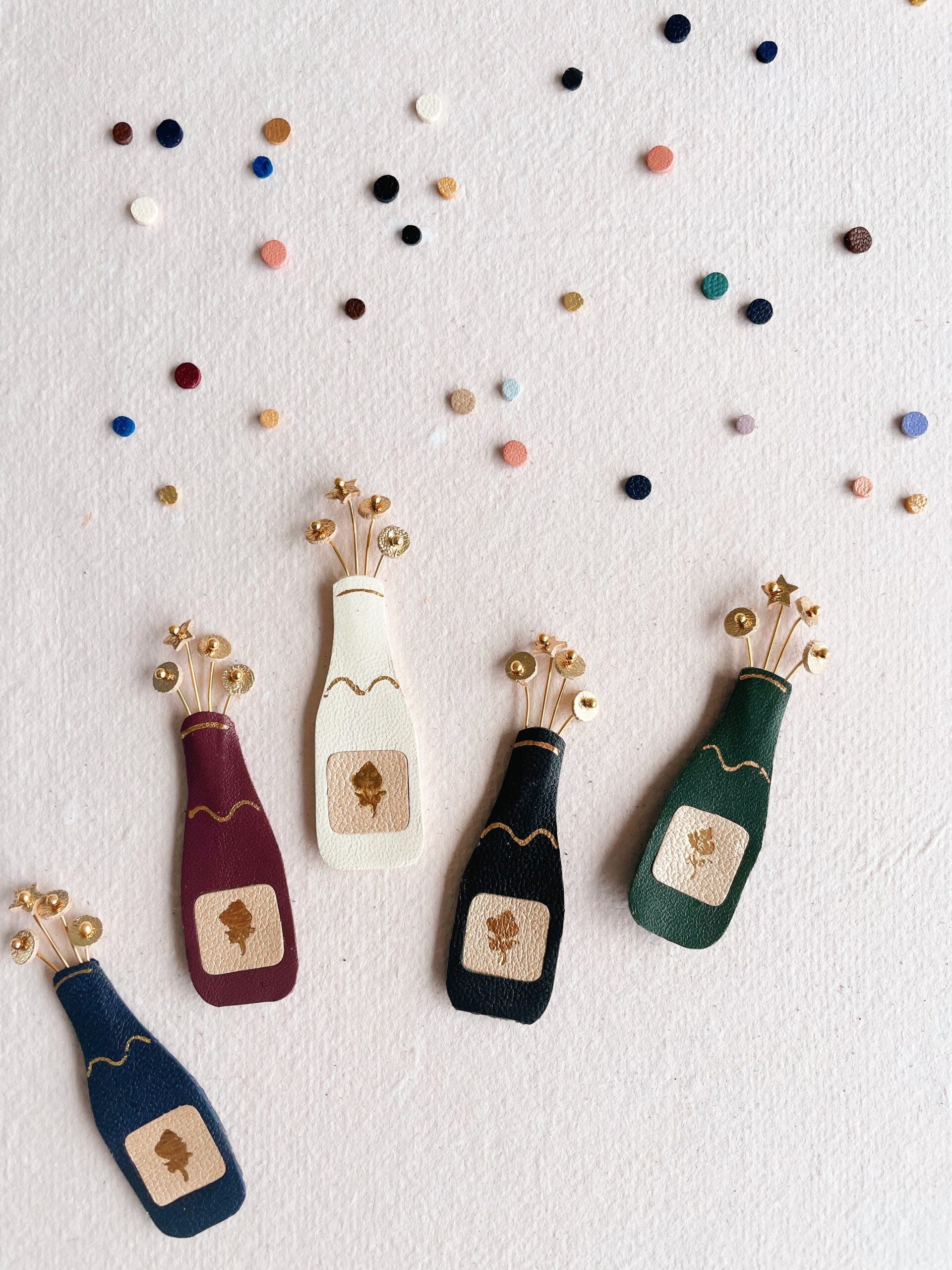 Broche pétillante façon bouteille de champagne artisanale – © Du vent dans mes valises 1 Broche bouteille de champagne artisanale en cuir avec bulles dorées