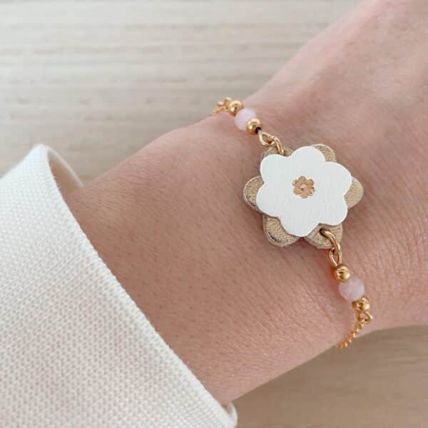 Bracelet Corolles fleur ivoire, quartz rose facetté et perles dorées, porté au poignet