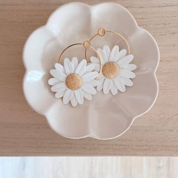 Boucles d’oreilles Marguerite blanches cœur doré en créoles, posées dans une coupelle