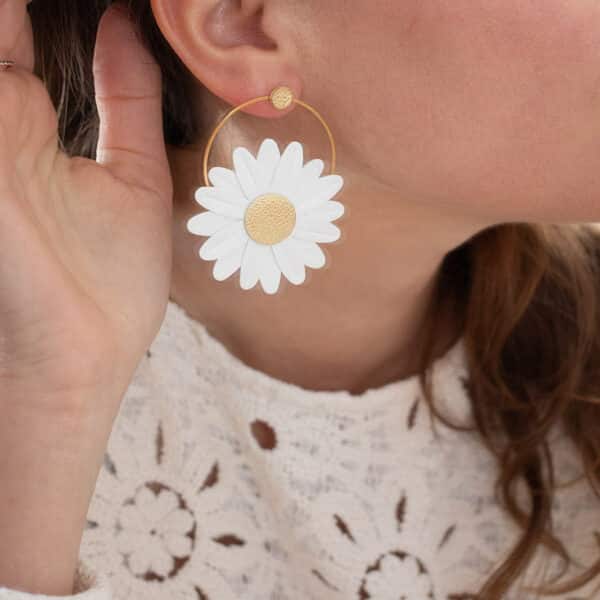 Boucle d'oreille marguerite en cuir blanc à cœur doré portée sur l'oreille, vue de profil rapprochée — bijou poétique artisanal Du Vent dans mes Valises