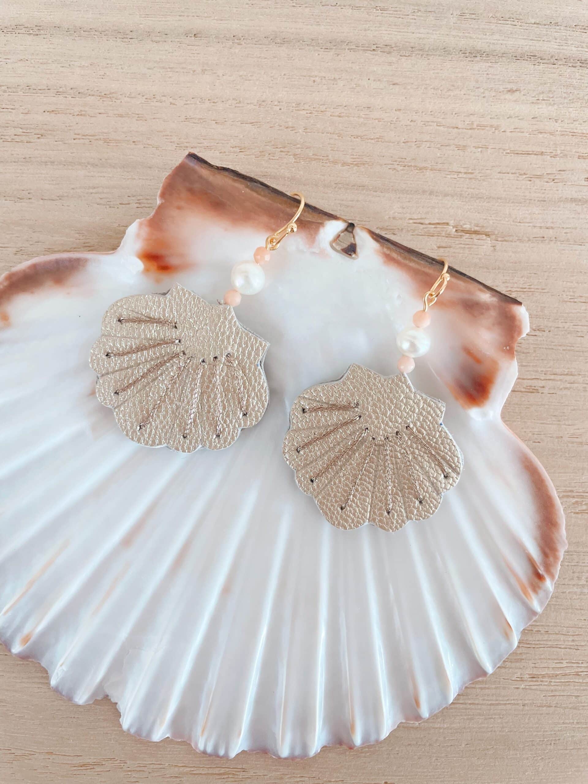 Boucles d'oreilles coquille cuir nacré — sur coquille naturelle © Du vent dans mes valises Boucles d'oreilles coquille en cuir nacré argenté posées sur une grande coquille naturelle, perle et quartz roses