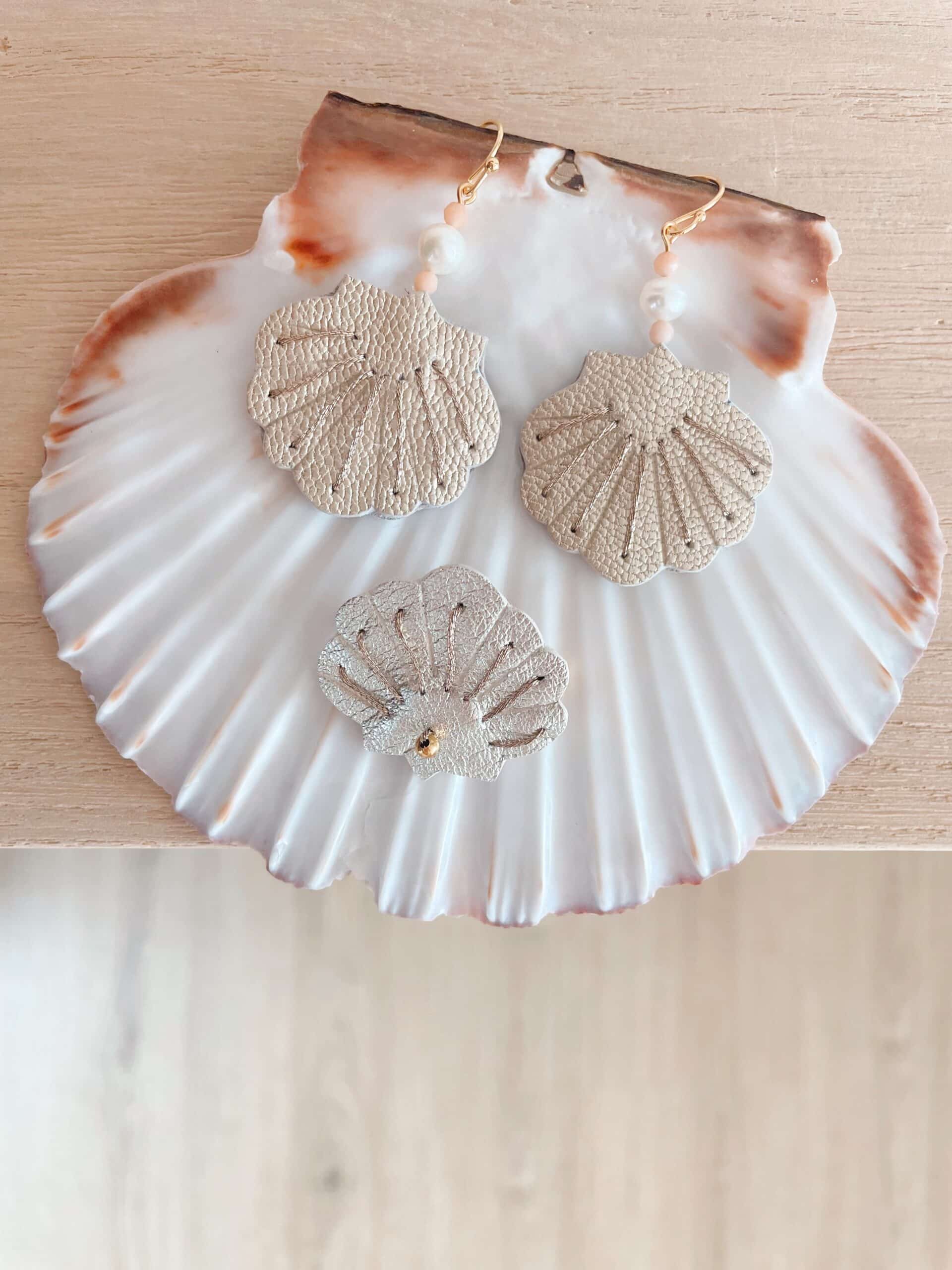 Broche et boucles d'oreilles coquille cuir nacré — sur coquille naturelle © Du vent dans mes valises Boucles d'oreilles et broche coquille en cuir nacré argenté posées sur une grande coquille naturelle, perle et quartz roses