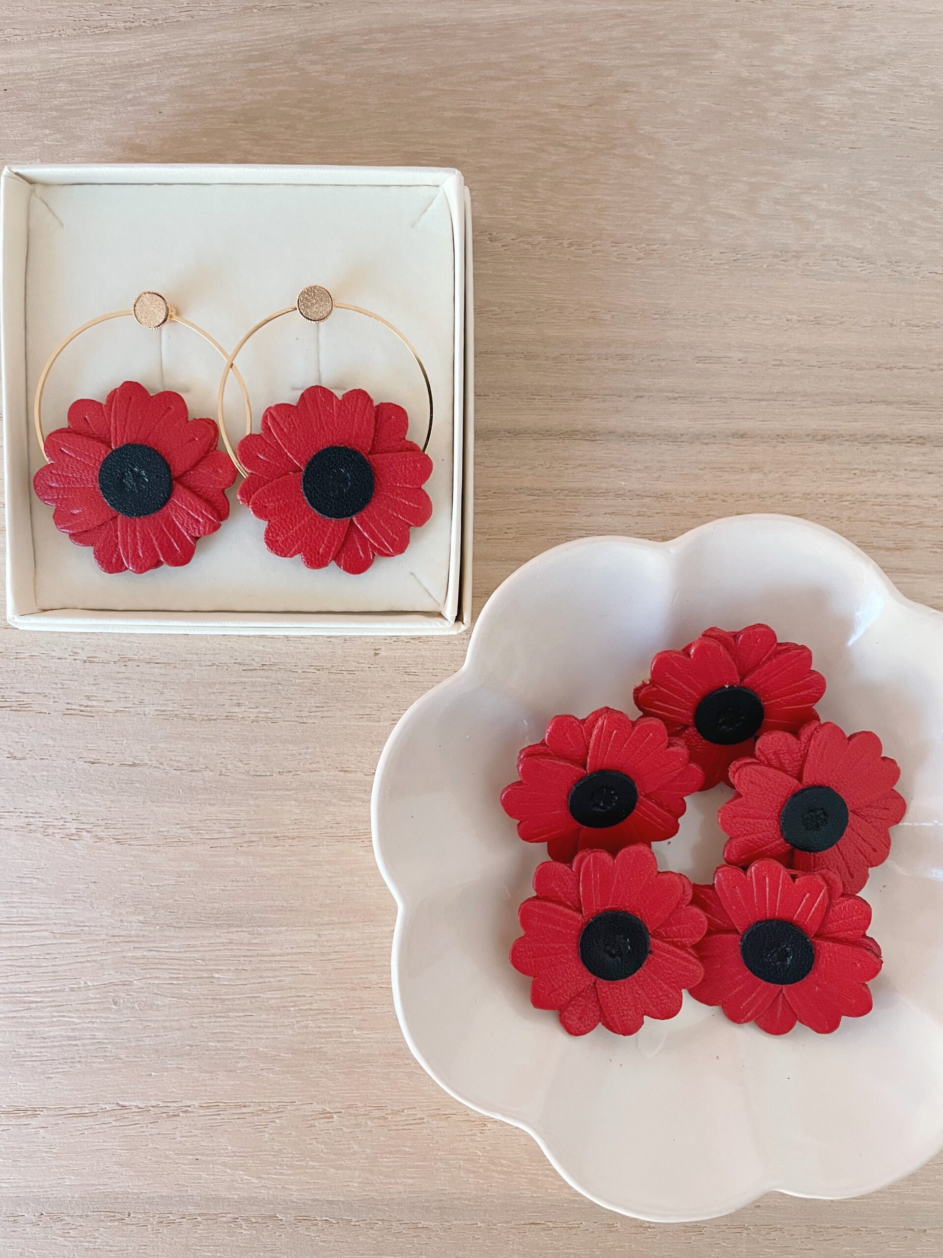 Boucles et broches coquelicot cuir — écrin et coupelle © Du vent dans mes valises Boîte de boucles d'oreilles coquelicot dorées et coupelle de broches coquelicot en cuir rouge
