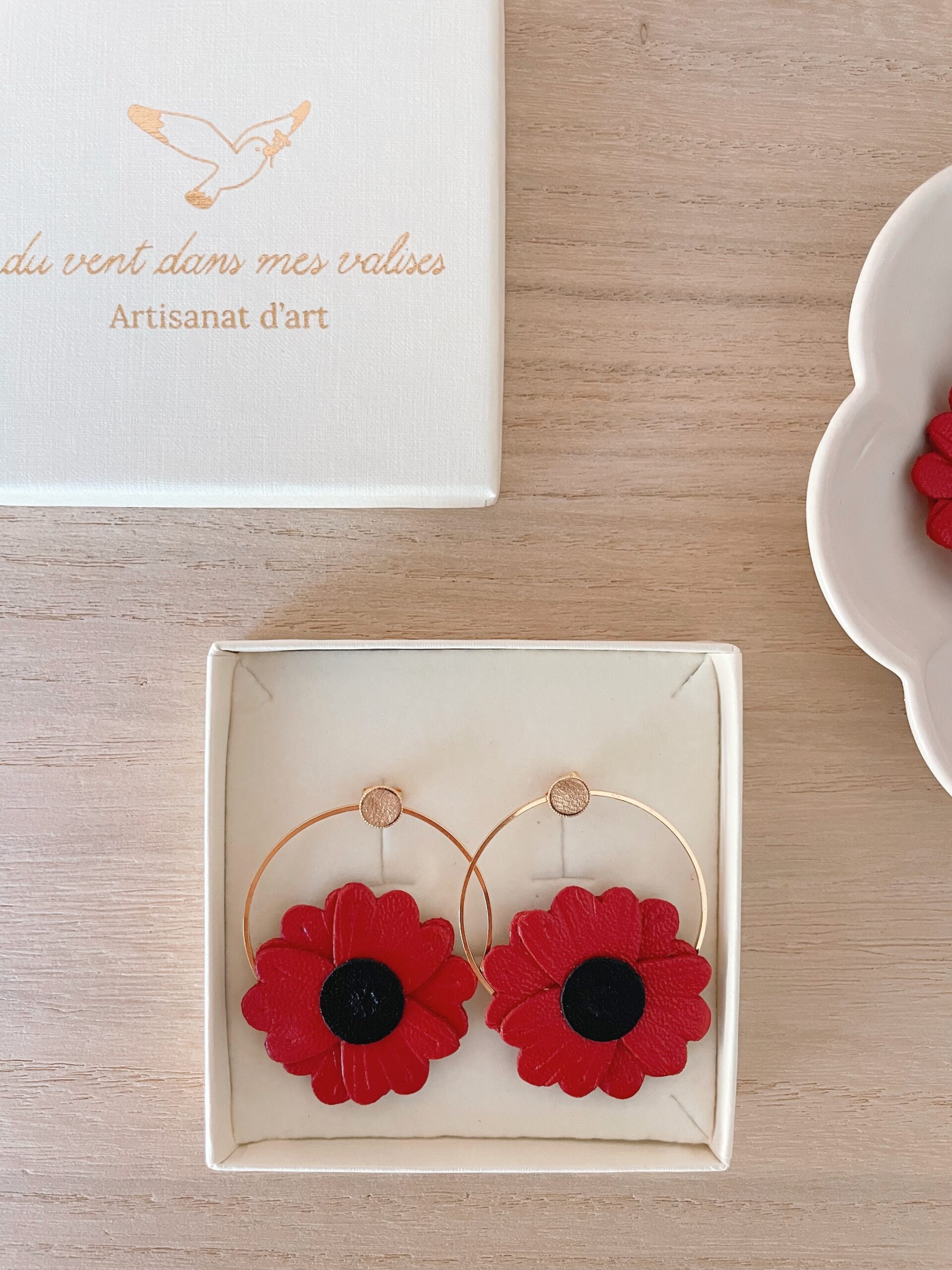 Boucles d'oreilles coquelicot cuir — écrin prêtes à offrir © Du vent dans mes valises Boucles d'oreilles coquelicot en cuir rouge dans leur écrin ouvert, boîte Du vent dans mes valises artisanat d'art