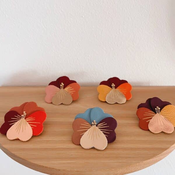 Cinq broches pensée chaleureuse en cuir surcyclé aux coloris d'automne — Gyroflee, Aubergine, Epices, Prunelle, Dhalia — sur plateau bois fond blanc