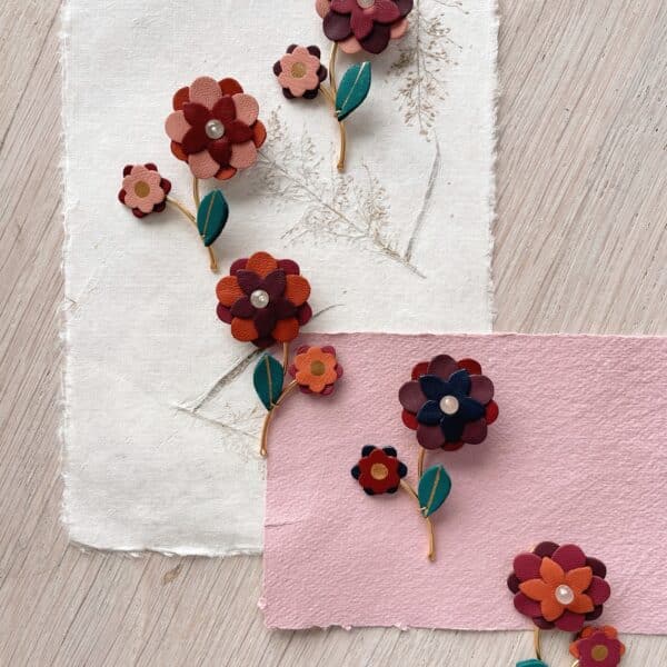 Broches Fleur Buissonnière en cuir surcyclé et dorure à l'or fin, mise en scène sur papier fait main et herbier séché, Du Vent dans mes Valises